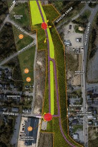 Aerial view of a road realignment project showing purple and yellow lanes with green buffers and orange boundary lines amid surrounding streets and neighborhoods.